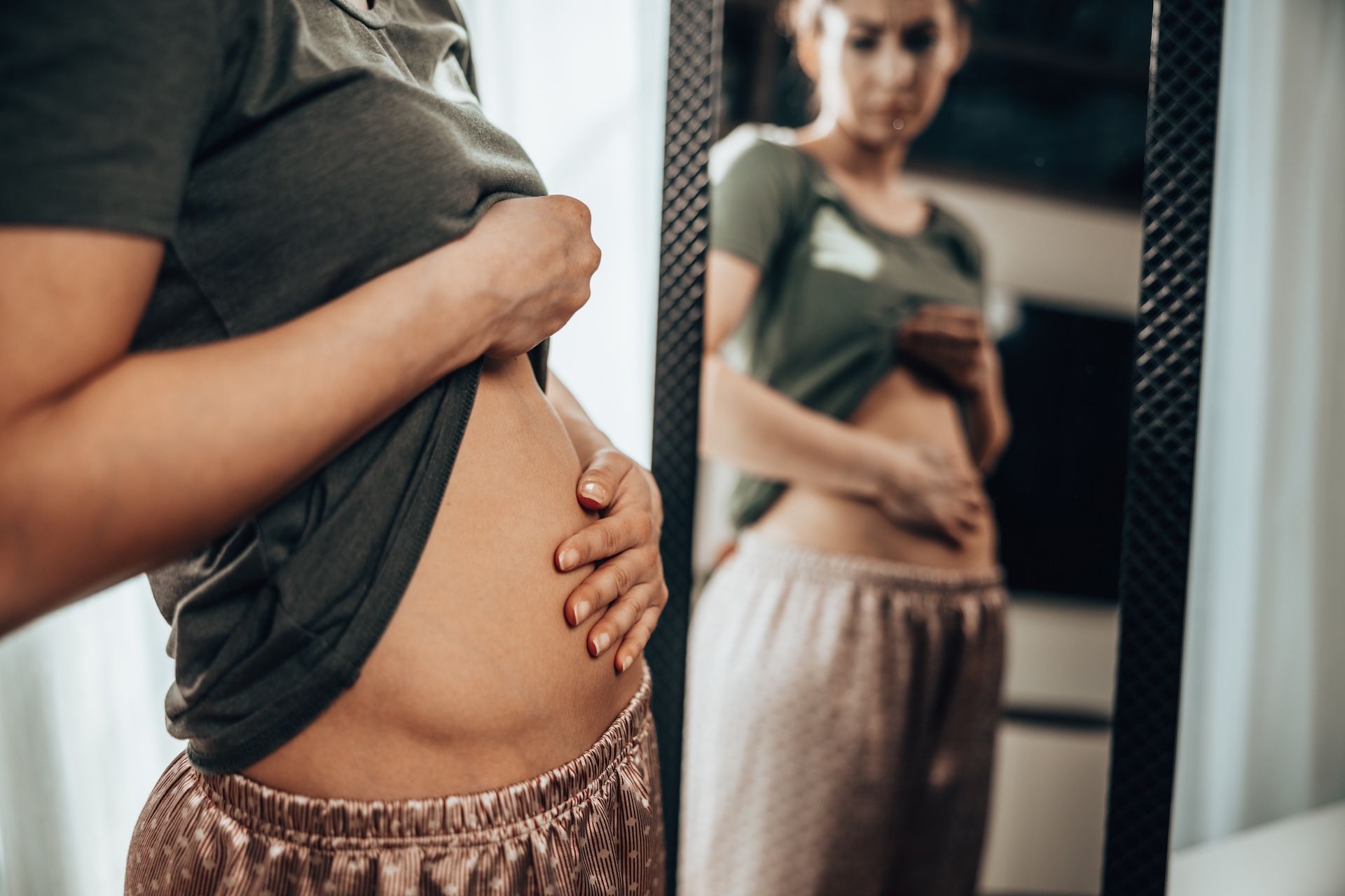 woman-touching-her-belly-while-standing-near-mirro-2026-03-10-04-00-23-utc.jpg